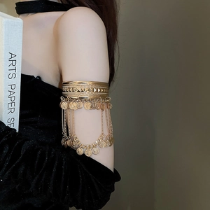 Close-up of golden bohemian armlet featuring embossed chevron patterns and coin tassels