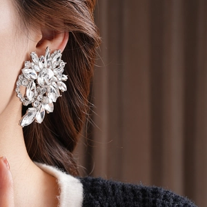 Detailed close-up of a silver oversized rhinestone floral earring worn by a model