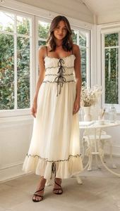 Détail de la robe trapèze crème avec liens contrastés noirs et finitions à volants doux