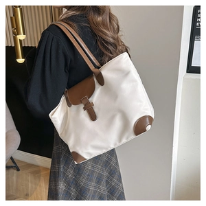 Detail of a large nylon tote bag featuring brown leather trim and contrast flap closure