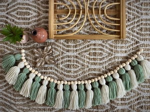 Detailed macro shot of green and white cotton tassels with natural wood beads on woven rug