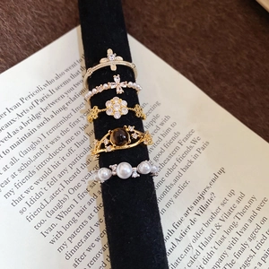 Close-up of five-piece vintage ring set with pearls and zircon on black velvet display