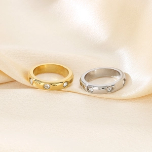 Detail of gold and silver stainless steel rings with crystals on silk background
