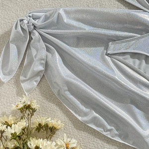 Détail du tissu de bikini argenté brillant avec paillettes irisées et nœud papillon latéral