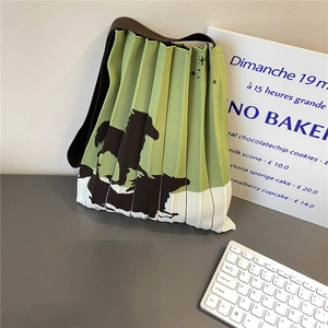 Detail of green pleated knit tote bag featuring a black horse pattern and brown strap