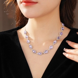 Detail view of a luxury purple teardrop gemstone necklace on model with diamond accents