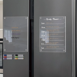 Close-up of two clear acrylic magnetic weekly planners with six markers on a dark grey fridge