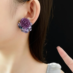 Close-up of vintage purple resin rose earrings with crystals on a model's ear