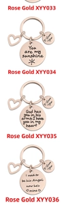 Close-up of four rose gold stainless steel round keychains with heart charm and engraving