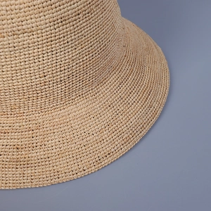 Detailed close-up of the fine texture and craftsmanship of the beige raffia straw sun hat