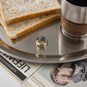 Detail of multi-layer mixed metal ring in gold and silver on a brushed steel tray