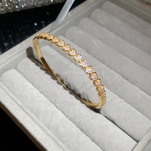 Vue macro d'un bracelet plaqué or 18k avec maillons en cœur et zircons étincelants