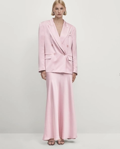 Detail view of pink satin blazer and midi skirt showing smooth silk-like fabric texture