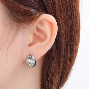 Macro shot of silver teardrop hoop earrings with star cutouts and sparkling cubic zirconia