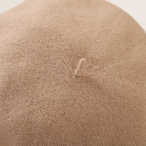 Macro detail of beige wool beret top showcasing soft fiber texture and stem detail
