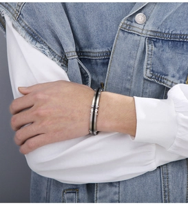 Detail of vintage carbon fiber buckle bangle in titanium steel on a male model's wrist