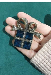 Detail of vintage gift box brooch with deep blue square stones and crystal bow