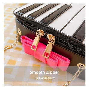 Detail of smooth gold zippers and large pink satin bow on the piano-themed bag