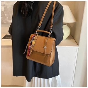 Detalle de la mochila de cuero marrón vintage con pañuelo de seda y colgante de raqueta