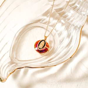 Detail of golden Our Lady of Guadalupe pendant necklace in a stylish glass dish