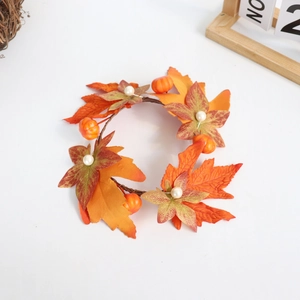 Close-up of autumn candle ring with maple leaves, mini pumpkins, and white berries