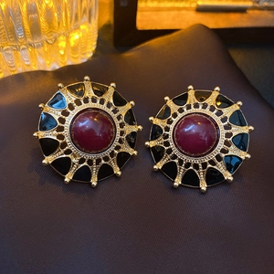 Détail macro de boucles d'oreilles vintage plaquées or avec pierre rouge et émail