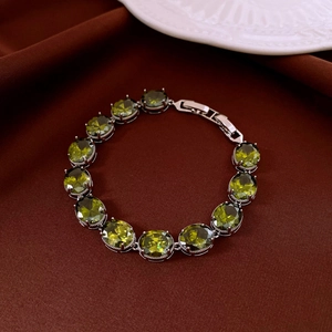 Macro shot of silver bracelet featuring 12 oval green zircons on dark velvet