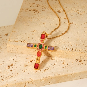 Gold stainless steel cross necklace with colorful zircon stones on beige travertine stone