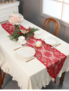 Close-up of red festive Christmas lace table runner with hollow floral pattern and tassels