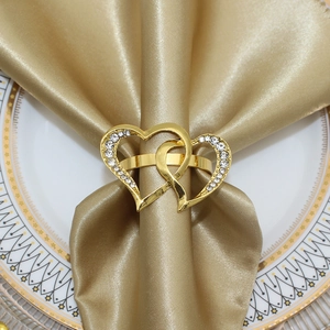 Close-up of interlocking gold heart napkin ring with rhinestones on a satin cloth