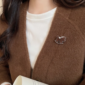 Detailed close-up of a vintage flocked pony brooch with crystals on a wool coat lapel