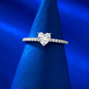 Macro shot of heart-cut gemstone ring with micro-pave diamonds on a blue stand
