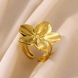 Elegant gold flower ring with textured petals on a beige satin background