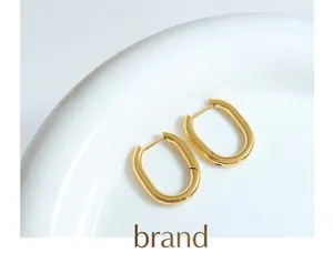 Macro view of gold U-shaped earrings with high-polish finish on a white ceramic plate
