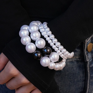 Détail d'un ensemble de bracelets multi-rangs en perles avec accents noirs sur manche