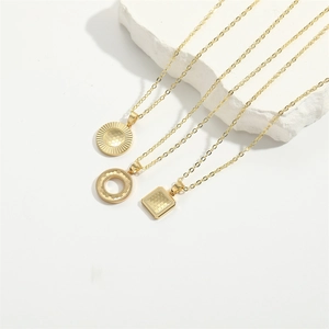 Three gold vintage round and square honeycomb pendant necklaces on white stone