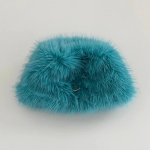 Detail of teal faux rabbit fur bucket hat with a metal triangle logo plaque