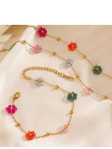 Detailed macro view of 18K gold plated chain with colorful bead flowers on silk fabric