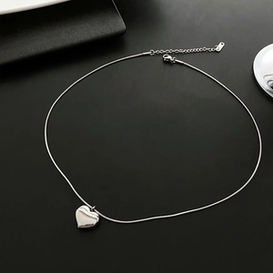Polished silver heart pendant necklace with adjustable chain on dark background