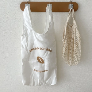 Foldable baguette eco-bag and cotton mesh net hanging on a wooden hook detail