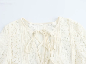 Detailed view of cream lace fabric texture and front tie-up design on the neckline