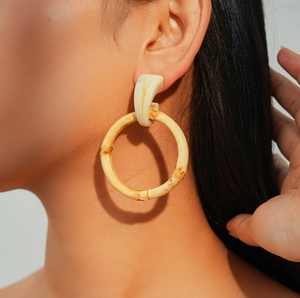 Close-up of bamboo hoop earring with marble pattern resin stud worn by a model