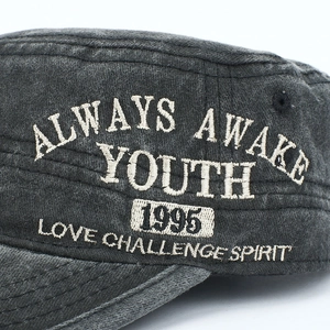 Close-up of Always Awake embroidery on washed black cotton baseball cap fabric