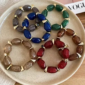 Acrylic oval beaded bracelets in dark glittery colors with gold metallic spacers