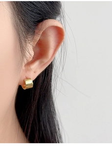 Close-up of a model wearing high-polish golden wide-band S925 silver hoop earrings