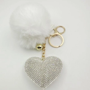 Detailed view of fluffy white pompom keychain with sparkling crystal heart pendant