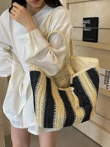 Vertical striped straw tote bag with tassels shown on model for summer beach vacation