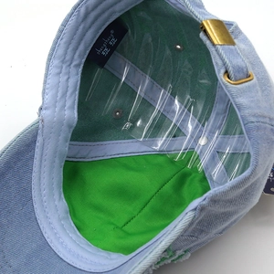 Detail of blue denim baseball cap interior featuring neon green lining and metal buckle