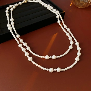 Close-up of double-layer white pearl necklace with magnetic clasp on elegant background