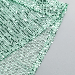 Close-up of mint green sequins on mesh fabric showing texture of the fishtail evening gown